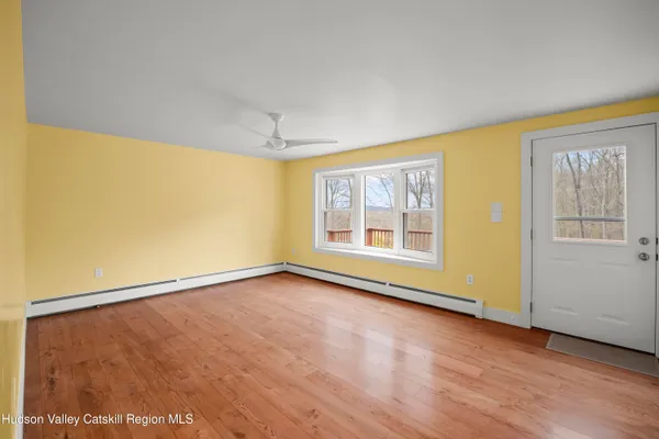 a view of an empty room with a window and wooden floor