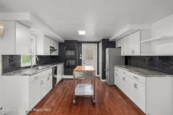 a kitchen with a refrigerator a sink and wooden floor