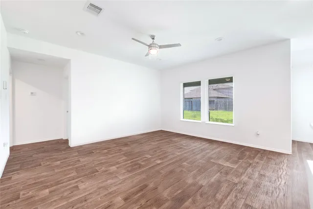 an empty room with windows and ceiling fan