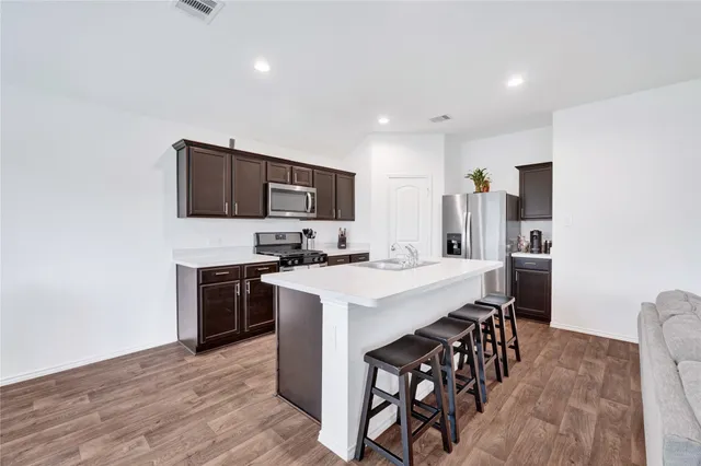 a kitchen with kitchen island a stove a sink a dining table and chairs