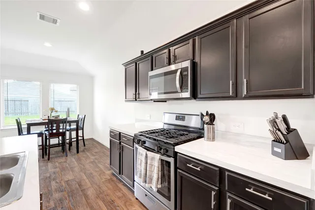 a kitchen with stainless steel appliances a stove a sink cabinets and a dining table