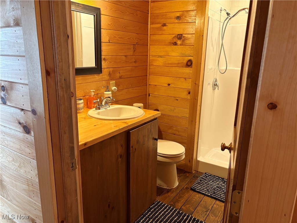 5919 Lake Road West, Unit 18 Ashtabula, OH 44004 - Photo 13 of 32 Full bathroom with a shower stall, dark wood-style flooring, vanity, and wooden walls