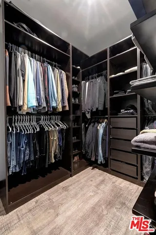 a view of walk in closet with clothes and shoes