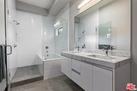 a bathroom with a double vanity sink a mirror and a shower