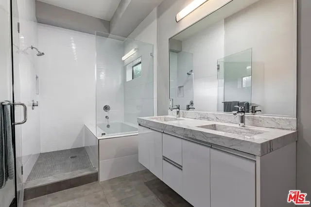 a bathroom with a double vanity sink a mirror and a shower