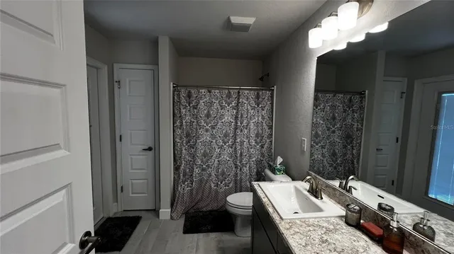 a bathroom with a granite countertop sink a toilet and shower