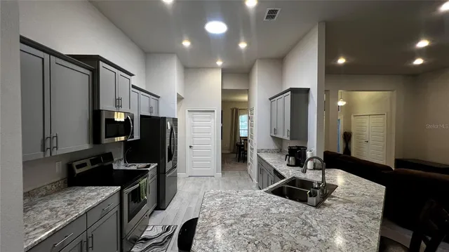 a kitchen with stainless steel appliances granite countertop a sink stove and refrigerator