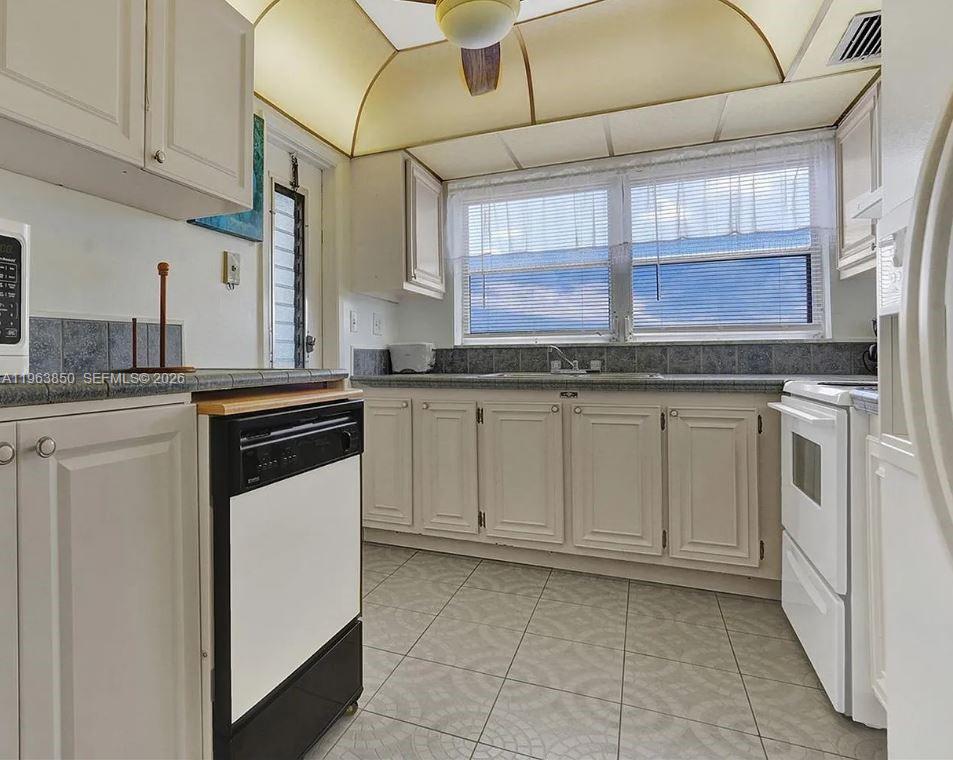 4047 Northwest 16th Street, Unit 403 Lauderhill, FL 33313 - Photo 12 of 22 a kitchen with granite countertop white cabinets and white appliances