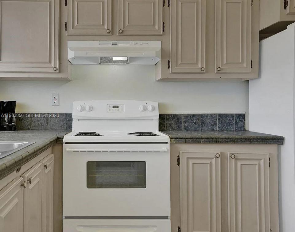 4047 Northwest 16th Street, Unit 403 Lauderhill, FL 33313 - Photo 13 of 22 a kitchen with granite countertop white cabinets and a stove