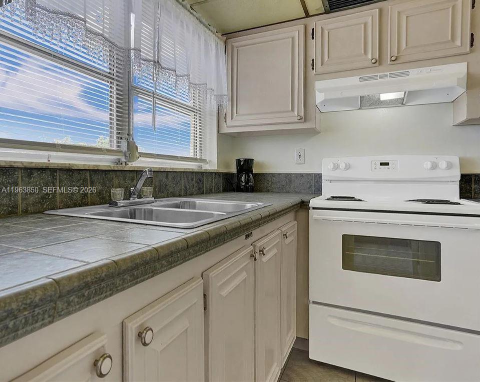 4047 Northwest 16th Street, Unit 403 Lauderhill, FL 33313 - Photo 14 of 22 a kitchen with stainless steel appliances granite countertop white cabinets and a counter top space