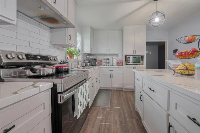 a kitchen with kitchen island granite countertop lots of white stainless steel appliances cabinets and a sink