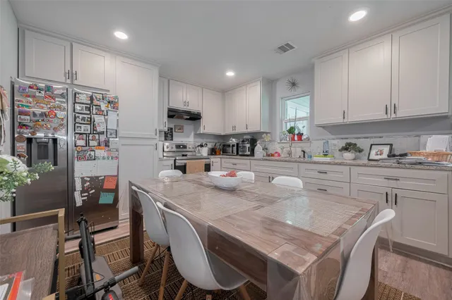 a kitchen with stainless steel appliances granite countertop a table chairs sink refrigerator and cabinets