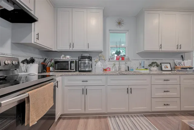 a kitchen with white cabinets and sink