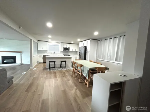 a kitchen with a table chairs a sink dishwasher refrigerator and cabinets