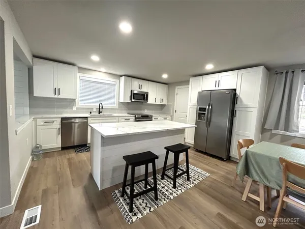 a kitchen with stainless steel appliances a table chairs refrigerator and a sink