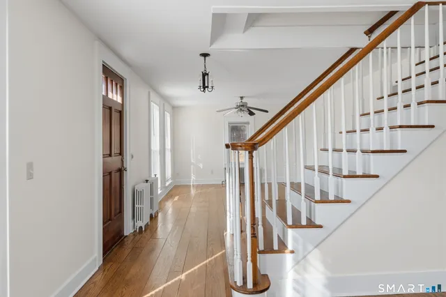 a view of staircase with wooden floor and white walls
