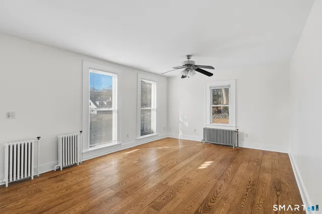 a view of an empty room with a window and wooden floor
