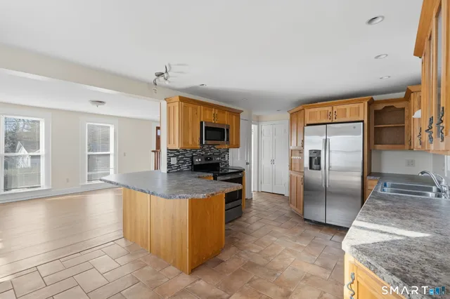 a kitchen with granite countertop a refrigerator a sink a stove and cabinets