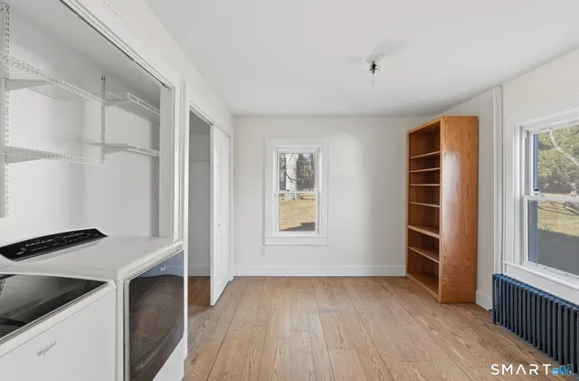 a view of an empty room with a window and wooden floor