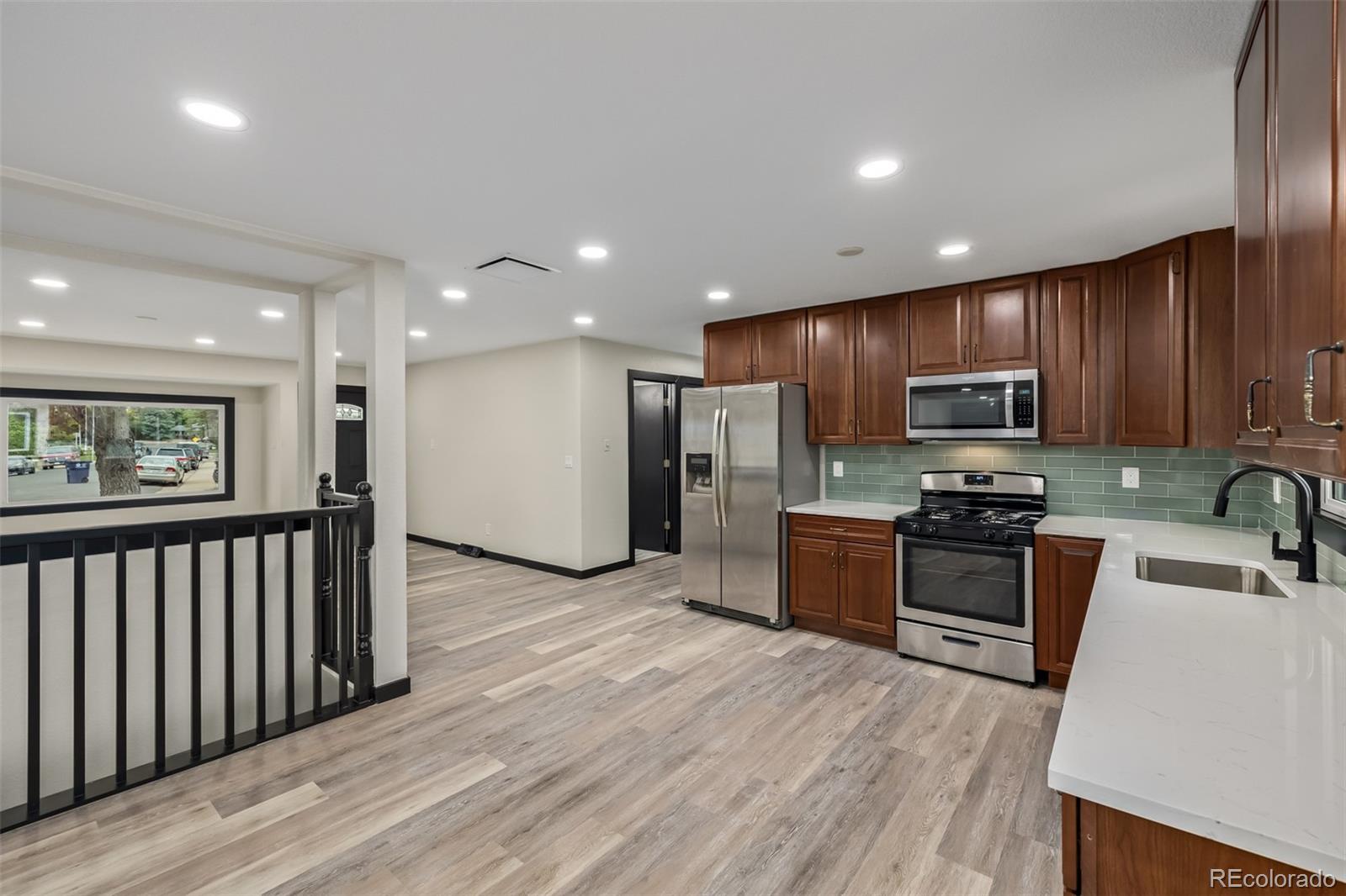 a kitchen with stainless steel appliances granite countertop a refrigerator a stove top oven a sink dishwasher and wooden cabinets with wooden floor