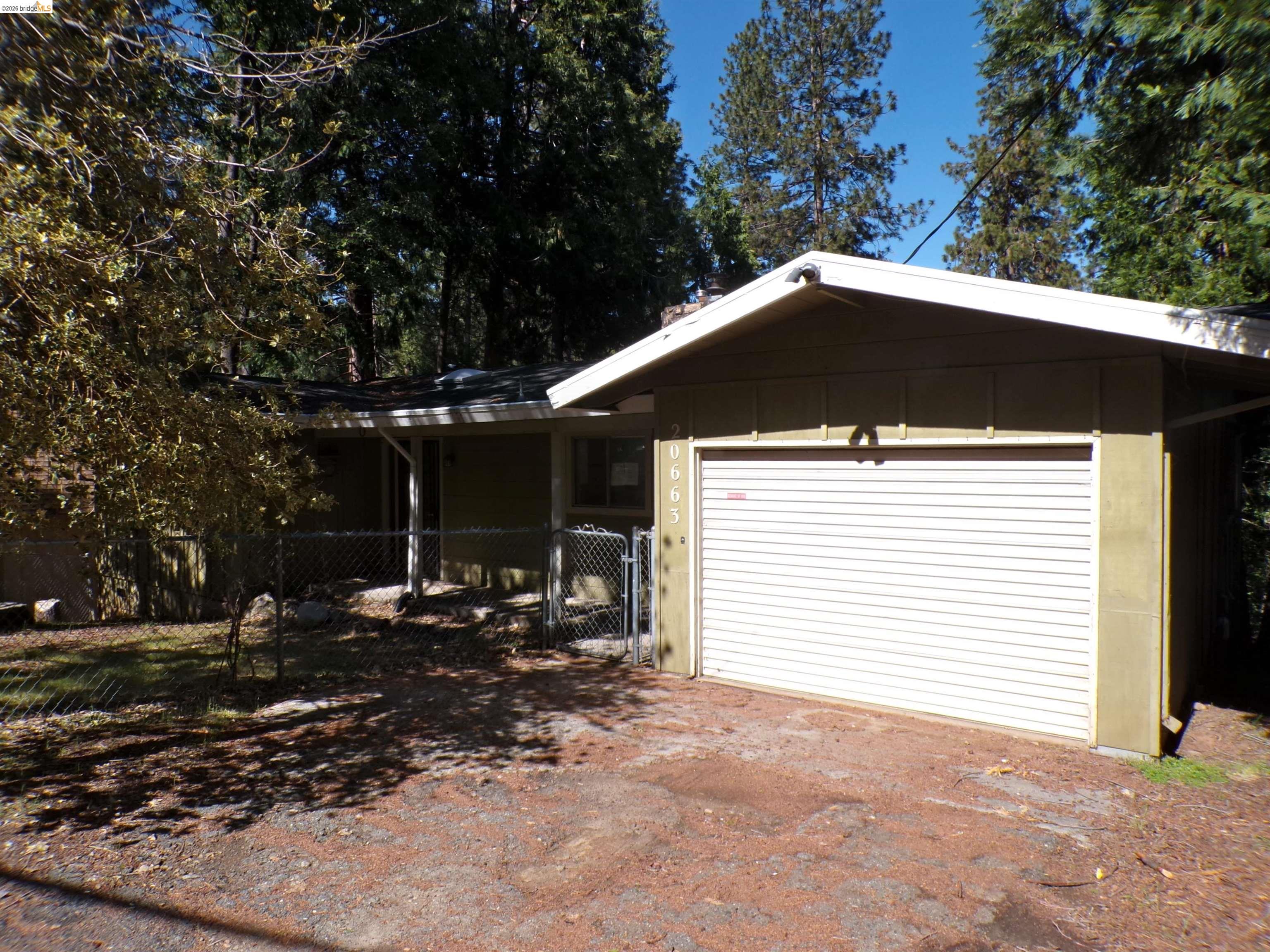 20663 Haiapo Road Mi Wuk Village, CA 95346 - Photo 3 of 24 a backyard of a house with table and chairs under an umbrella
