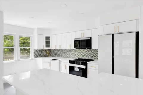a kitchen with stainless steel appliances kitchen island a white stove top oven and a refrigerator with white cabinets