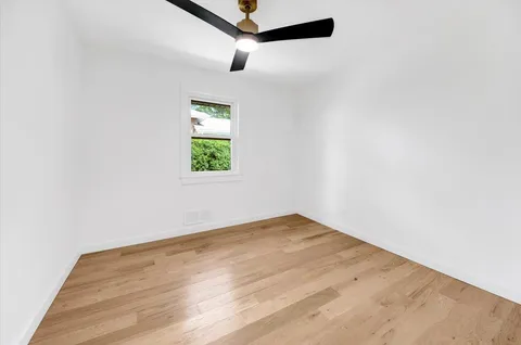 a view of empty room with window and ceiling fan