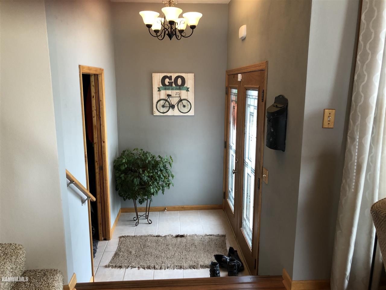 7695 East Winneshiek Road Ridott, IL 61067 - Photo 2 of 15 a view of a hallway with wooden floor and a chandelier