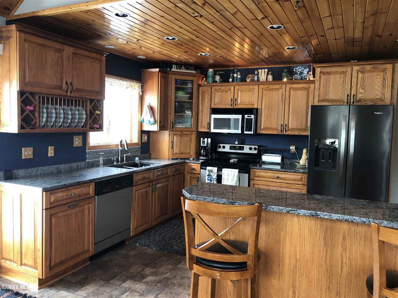 7695 East Winneshiek Road Ridott, IL 61067 - Photo 6 of 15 a kitchen with kitchen island granite countertop wooden cabinets a refrigerator a sink a stove and a microwave