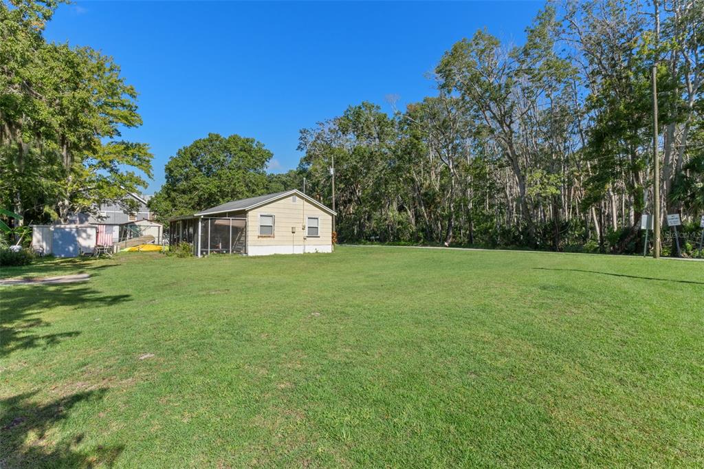 5492 Ramada Street Weeki Wachee, FL 34607 - Photo 22 of 25 a view of a white house in front of a big yard with plants and large trees