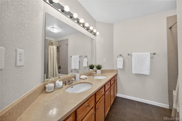 a bathroom with a granite countertop double vanity and a mirror