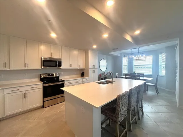 a large kitchen with kitchen island granite countertop a stove a sink a dining table and chairs