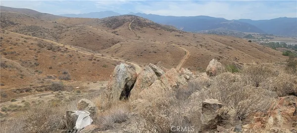 a view of a dry yard with mountains in the background
