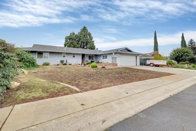 a front view of a house with a garden and trees