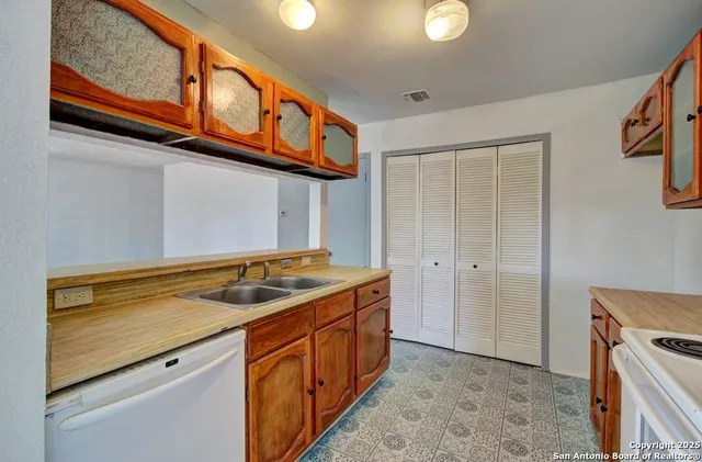 a utility room with stainless steel appliances granite countertop a sink and dishwasher a stove with wooden floor