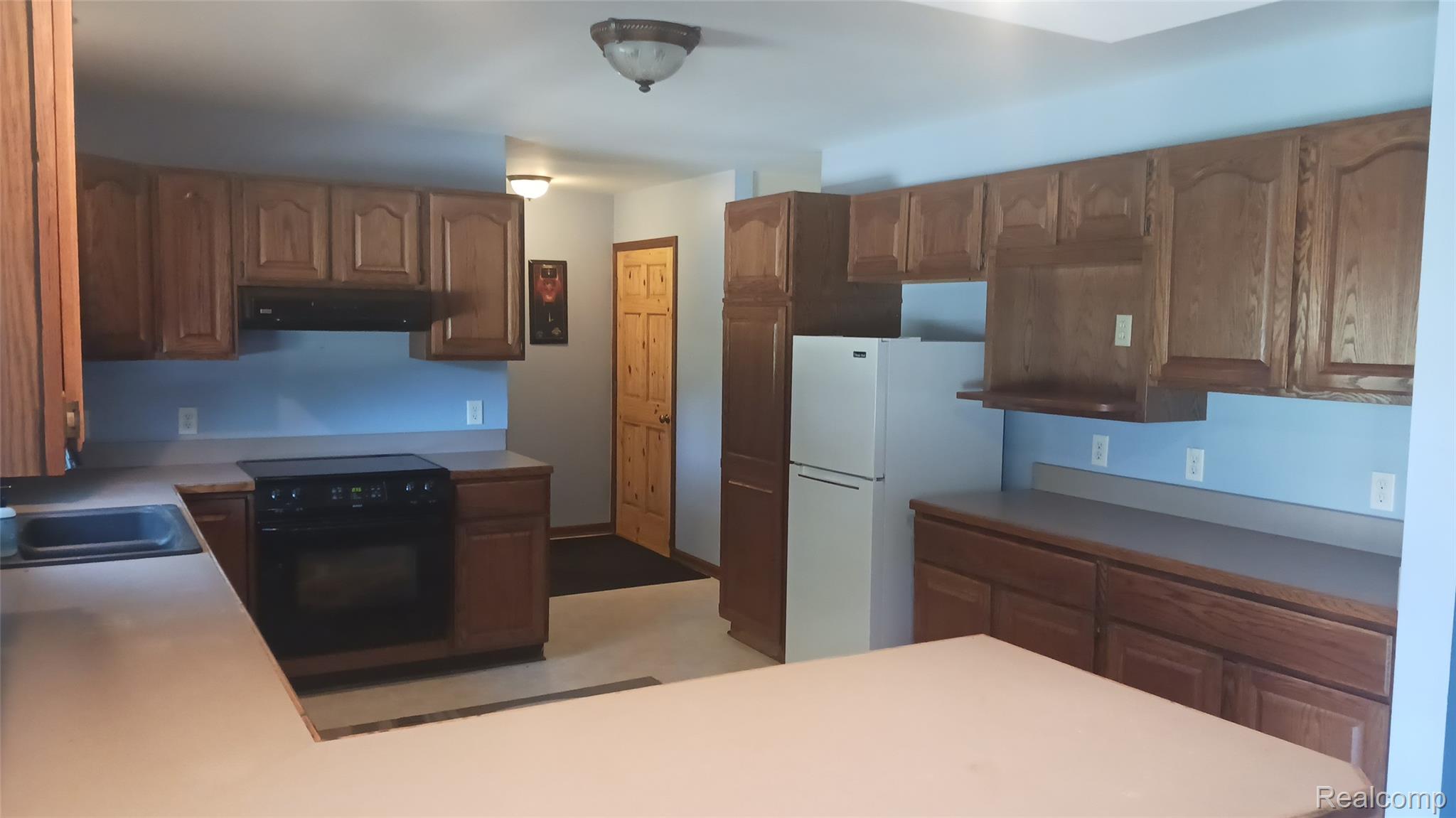3803 Warner Road Cass City, MI 48726 - Photo 21 of 85 Kitchen with brown cabinetry, black appliances, range hood, and light countertops