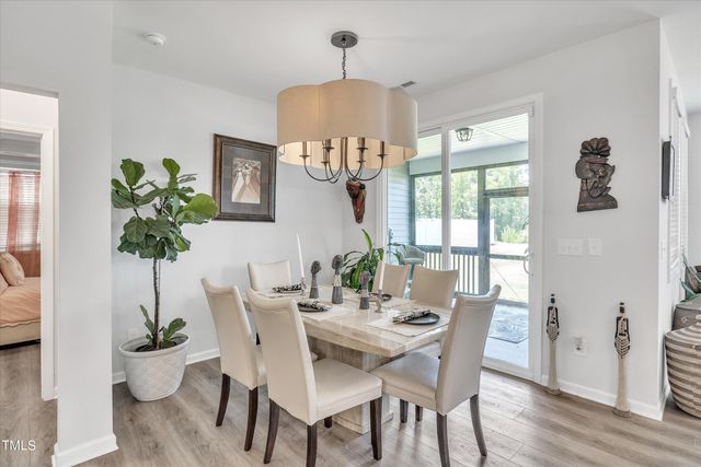 a dining room with furniture potted plants and wooden floor