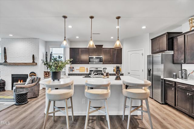 a kitchen with refrigerator a stove a dining table and chairs with wooden floor