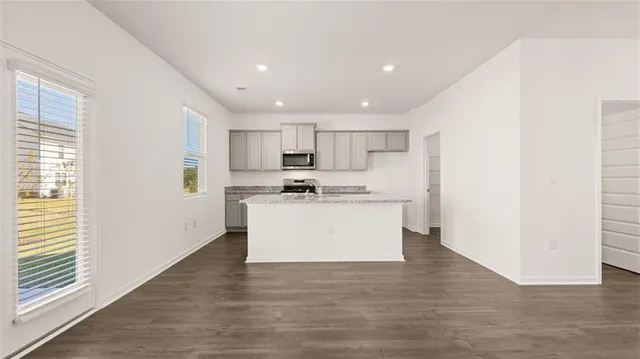 a view of kitchen with granite countertop refrigerator oven sink and white cabinets with wooden floor