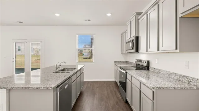 a kitchen with stainless steel appliances granite countertop a sink and dishwasher a stove top oven with wooden floor