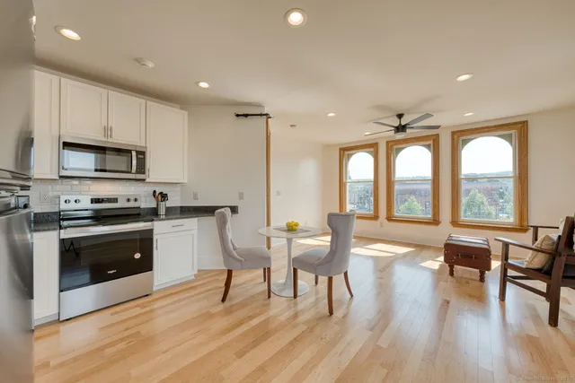 a living room with stainless steel appliances furniture and a wooden floor