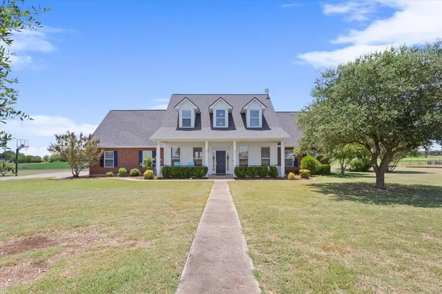 a front view of a house with a yard and trees