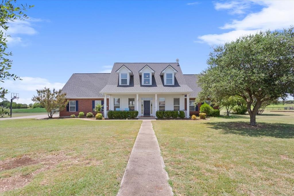 a front view of a house with a yard and trees