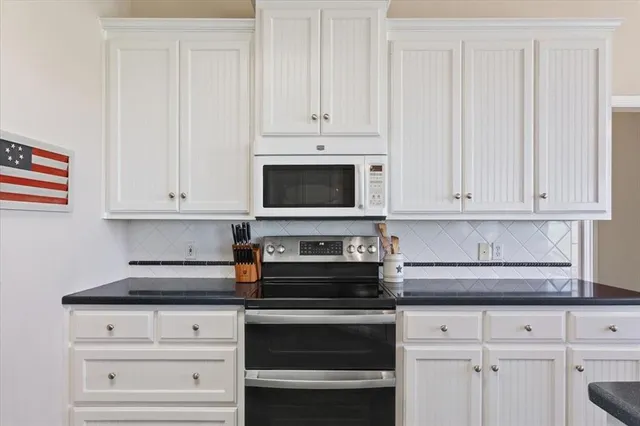 a kitchen with white cabinets and black appliances