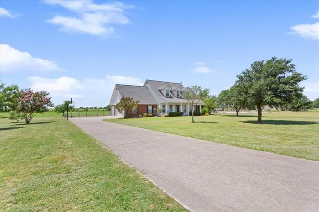 a view of a house with a big yard and a large trees