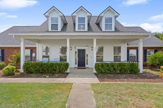 a view of a brick house with a yard plants and large trees