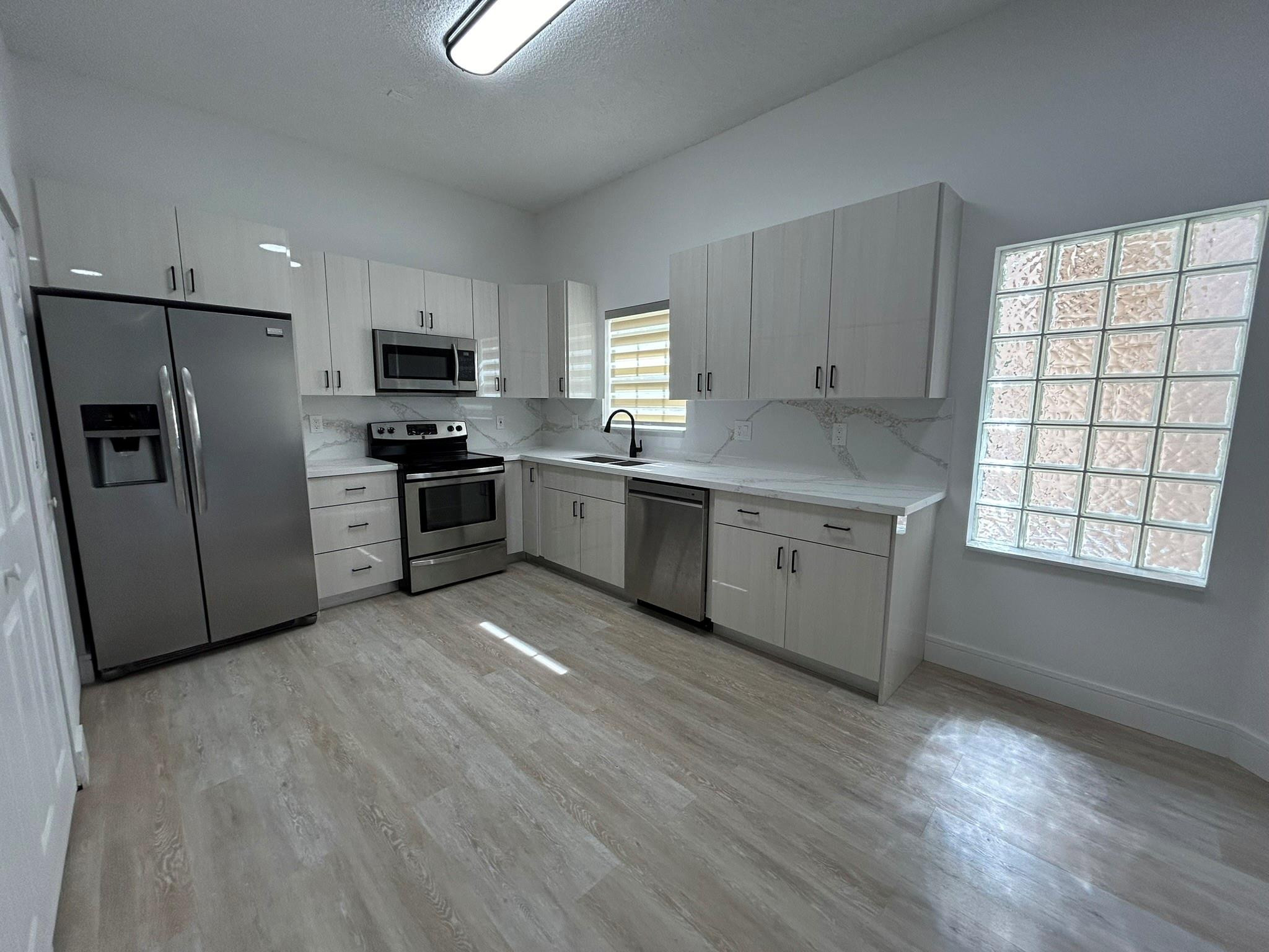 16223 Emerald Cove Road, Unit 16223 Weston, FL 33331 - Photo 10 of 38 a kitchen with stainless steel appliances granite countertop a stove a sink dishwasher a refrigerator and a microwave oven with wooden floor