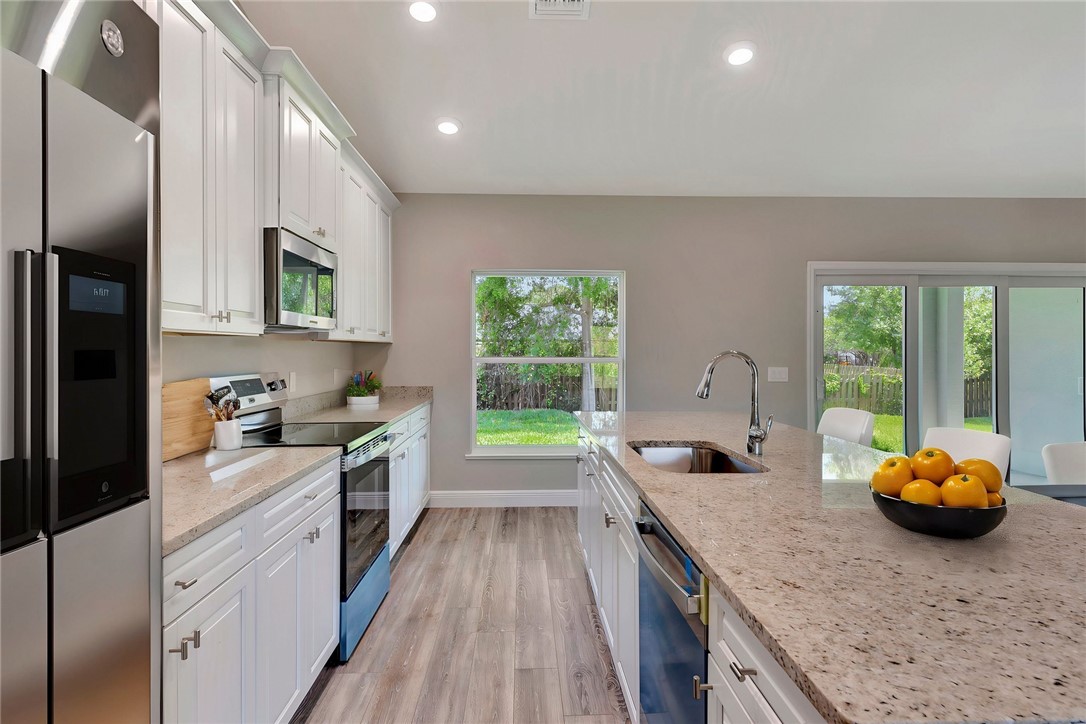 11126 Roseland Road Sebastian, FL 32958 - Photo 3 of 7 a kitchen with stainless steel appliances granite countertop a sink a stove and a wooden floors
