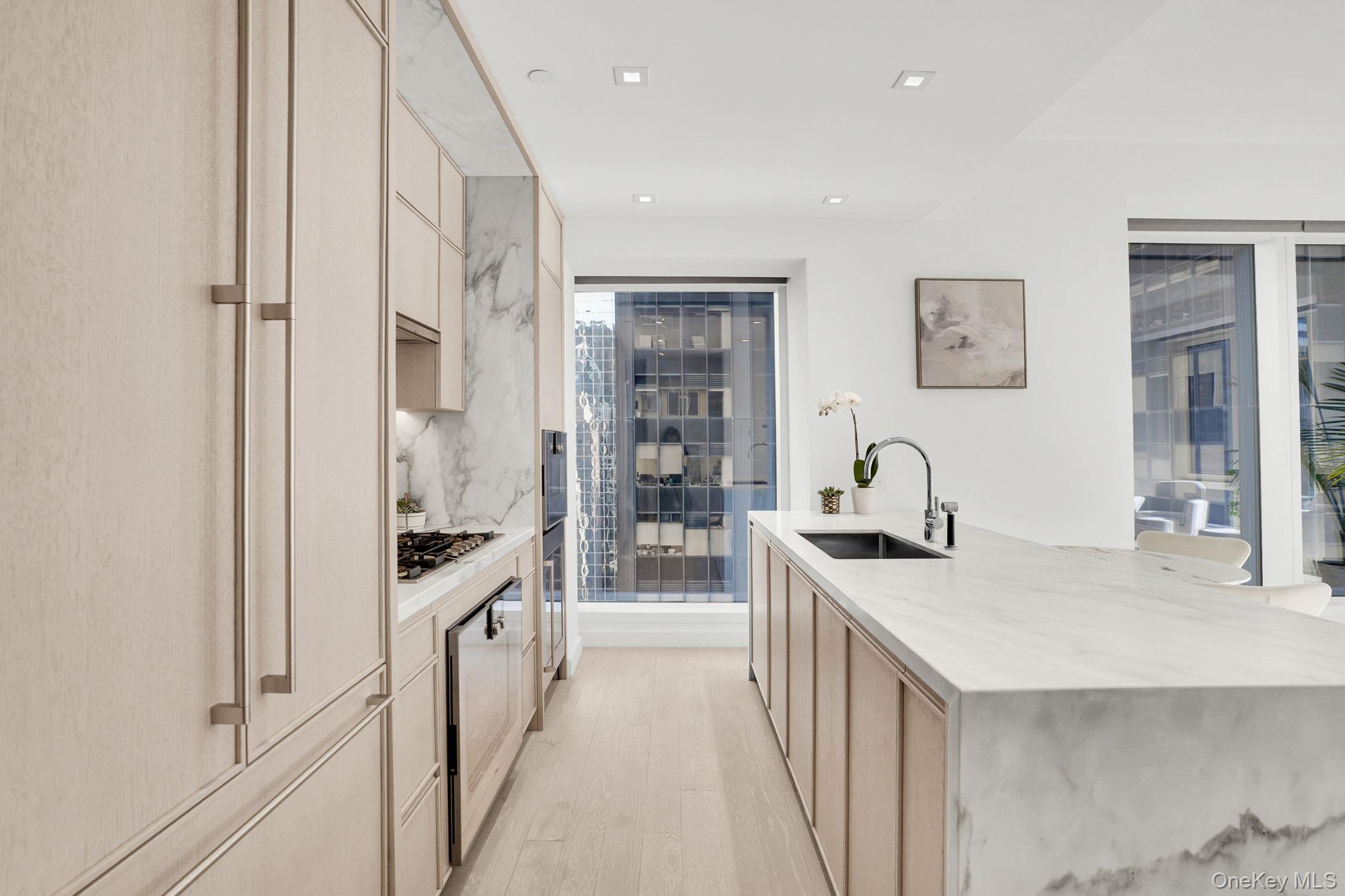 138 East 50th Street, Unit 26C Manhattan, NY 10022 - Photo 11 of 31 a kitchen with white cabinets and sink