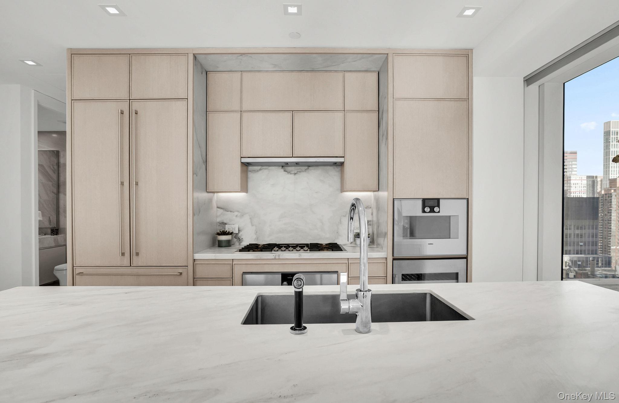 138 East 50th Street, Unit 26C Manhattan, NY 10022 - Photo 12 of 31 a kitchen with kitchen island granite countertop a sink and a stove with white countertops